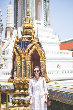 a woman standing in front of a large golden building with ornate decorations on it's sides