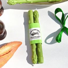 asparagus wrapped in green paper next to bread and wine glasses