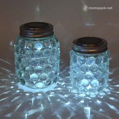 two glass jars sitting on top of a table covered in frosted glass balls and lids