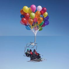 a group of people riding on top of a ski lift filled with lots of balloons