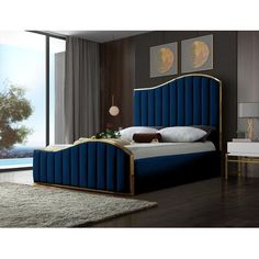 a blue bed with gold trim and headboard in a room next to a large window