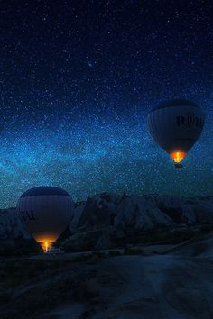 three hot air balloons flying in the night sky