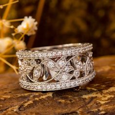 a close up of a wedding ring on a rock with flowers in the background,