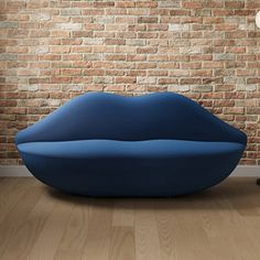 a blue couch sitting in front of a brick wall next to a lamp and chair