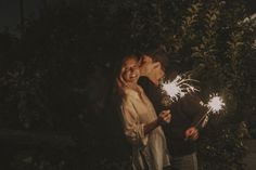 a man and woman standing next to each other holding sparklers