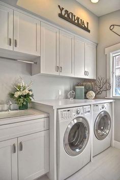 a washer and dryer in a white laundry room with lots of cabinet space