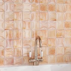 a sink with a faucet in front of a tiled wall