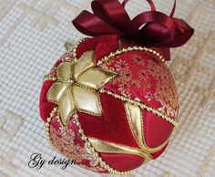 a red and gold ornament with a bow on it