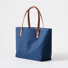 The Navy Canvas East West Tote is a canvas and leather tote handmade in the KMM & Co. studio in Atlanta. Each one is meticulously crafted from heavyweight canvas and gorgeous full-grain leather. Navy Canvas is a type of cotton canvas known as duck cloth. It's one of the most durable types of cloth, and it's structured enough to stand up on its own. The Navy Canvas East West Tote comes standard with Tan handles. Blue Canvas Bag With Canvas Lining, Classic Canvas Bag For Daily Use, Blue Canvas Shoulder Bag With Leather Trim, Duck Cloth, East West, Full Grain Leather, Canvas Tote, Leather Tote, Cotton Canvas