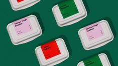 four white containers with red and green labels on the lids are lined up against a green background