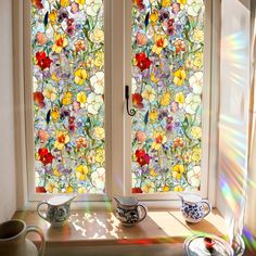 the sun shines through two stained glass windows with matching cups and saucers in front of them