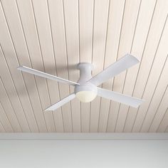 a white ceiling fan mounted on the side of a wooden paneled wall in an empty room