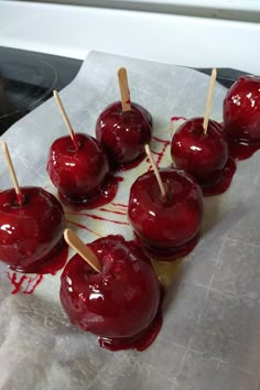 some candy apples with toothpicks in them sitting on a tray covered in blood