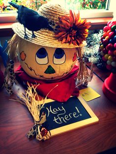 a pumpkin decorated like a scarecrow with a sign that says hey there