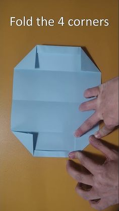 two hands reaching for an origami object with the text fold the 4 corners