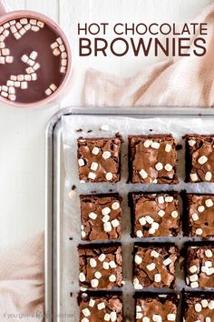 chocolate brownies with marshmallows are on a baking sheet next to a cup of coffee