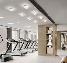 there are many treadmills in the gym with lights on them and some bookshelves