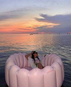 a woman sitting in an inflatable chair on the water at sunset or dawn