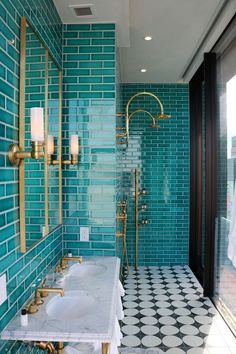 a bathroom with two sinks and blue tiles on the walls, along with gold faucets