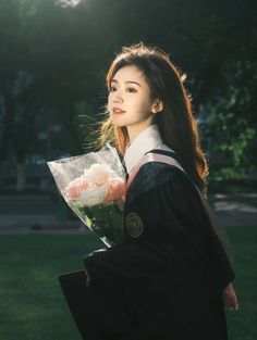 a young woman in graduation gown holding flowers