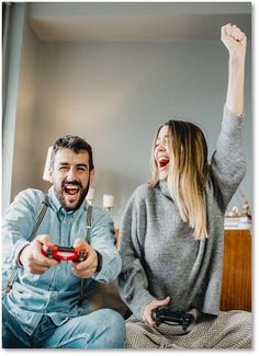 a man and woman sitting on a bed playing video games together with remote controllers in their hands