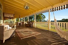 a porch with hammock chairs and an area rug on the wooden flooring