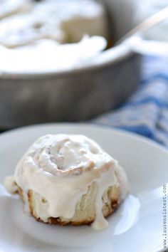 a white plate topped with a cinnamon roll covered in icing