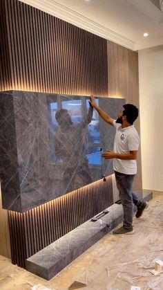 a man standing in front of a marble wall with his hand on the glass window