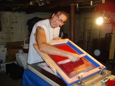 a man in white shirt working on an art piece with red and blue squares around it