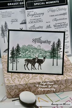 a card with two deer standing next to each other on top of a table in front of some papers