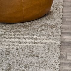 a brown leather ottoman sitting on top of a wooden floor next to a white rug