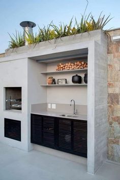 an outdoor kitchen is built into the side of a building with plants growing on top