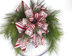 a christmas wreath with red and white ribbons