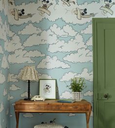 a wooden table sitting in front of a wall with clouds and mickey mouses on it