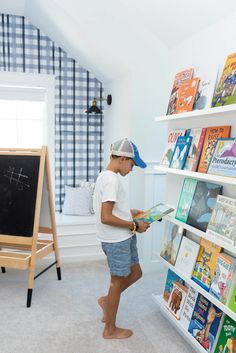 a young boy standing in front of a bookshelf with many books on it