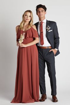 a man and woman standing next to each other in formal wear, posing for the camera