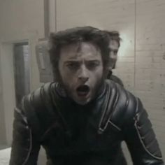 a man with his mouth wide open standing in front of a mirror wearing a leather jacket