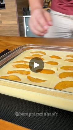 a person standing in front of a baking pan filled with doughnuts on top of a wooden table