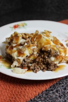 a white plate topped with meat and cheese covered in sauce