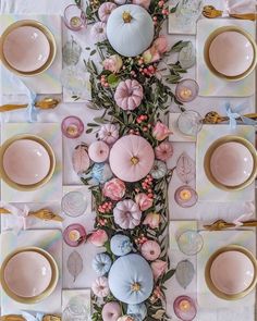 the table is decorated with pastel pinks, blue and gold plates and flowers