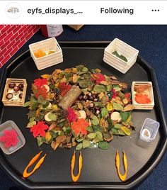 a black tray topped with lots of different types of fall leaves