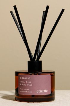 a bottle with some sticks sticking out of it's top on a white surface