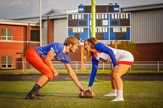 a man and woman in football uniforms kneeling down to pick up a ball from the ground