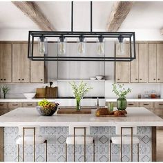 a large kitchen island with stools and lights hanging from it's ceiling over the counter