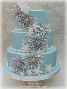 a blue and white cake with snowflakes on the top is decorated with flowers