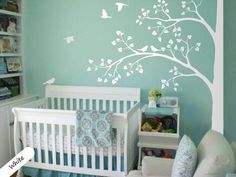 a baby's room with a white crib and pink tree decal