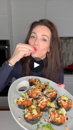 a woman is holding a plate with sushi on it