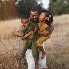 three young children are hugging each other in the middle of a field with tall grass