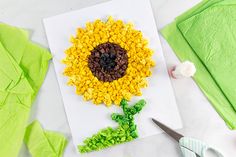 a sunflower made out of cereal sitting on top of a piece of paper next to scissors