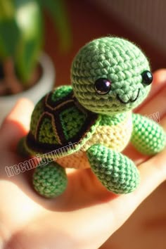 a small crocheted turtle sitting on someone's hand